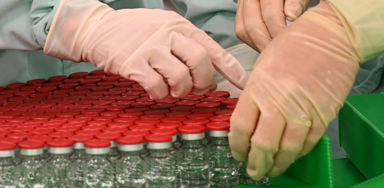 Laboratory technicians handle capped vials as part of filling and packaging tests for the large-scale production and supply of the University of Oxford’s COVID-19 vaccine candidate, AZD1222. Credit: AFP