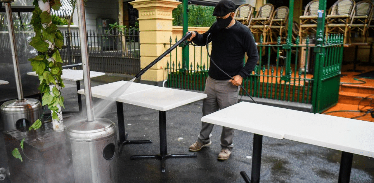 A man cleans as restaurants and cafes prepare for opening in Melbourne on October 27, 2020, as the state government lifts some restrictions on retail and restaurants after the city battled a second wave of the Covid-19 coronavirus. Credit: AFP Photo