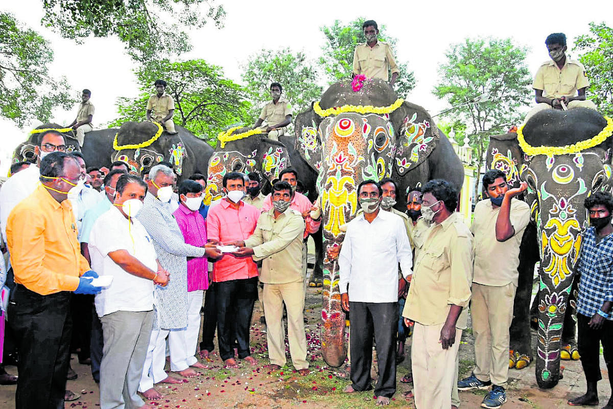 District In-charge Minister S T Somashekar presents honorarium to mahouts and kavadis at Mysuru Palace on Tuesday. MLAs S A Ramadass and L Nagendra and MUDA Chairman H V Rajeev are seen. DH PHOTO