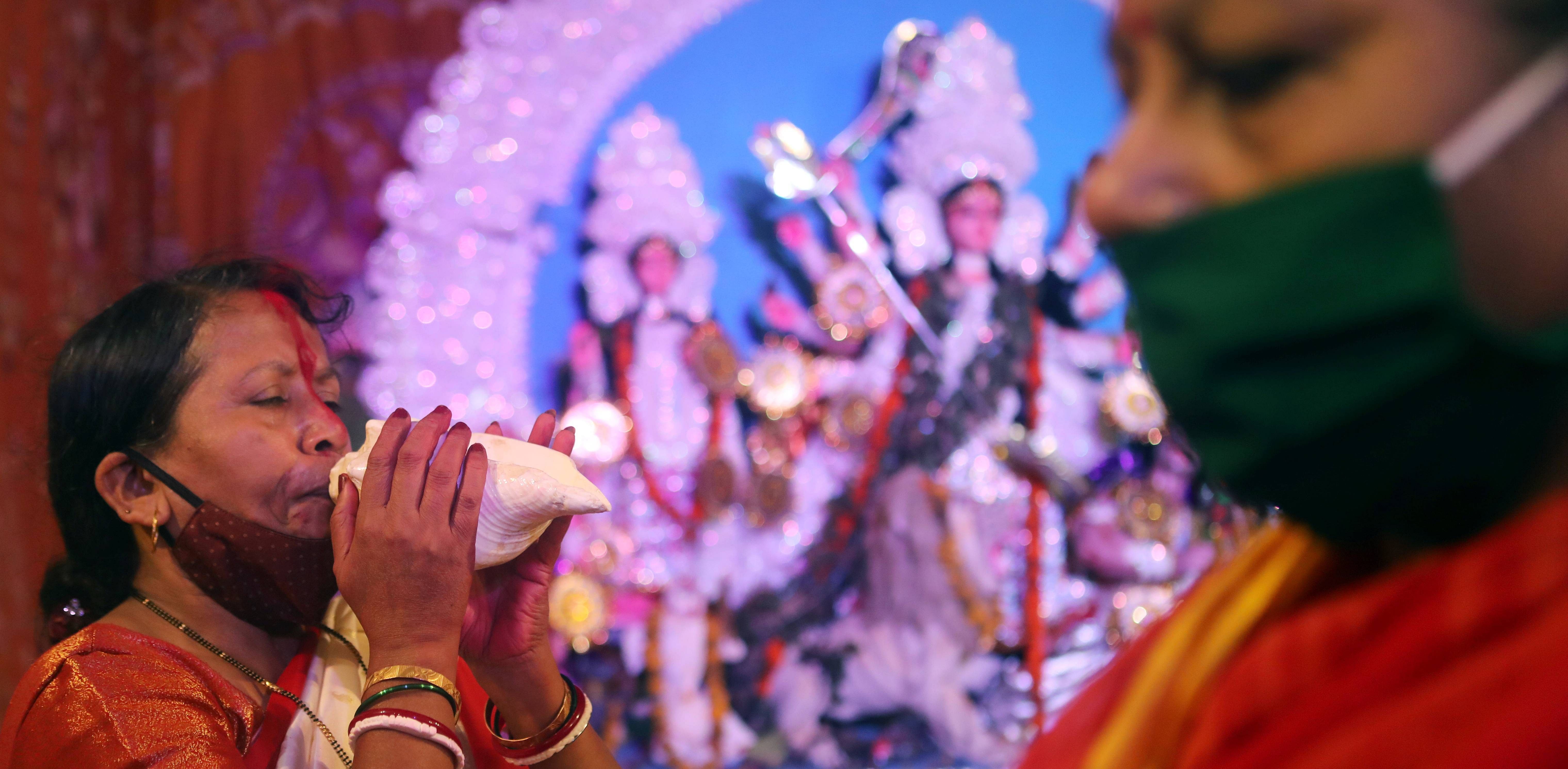 A Hindu devotee blows a conch shell during Durga Puja celebrations at a pandal, amidst the spread of the coronavirus disease (COVID-19) in Mumbai. Credit: Reuters