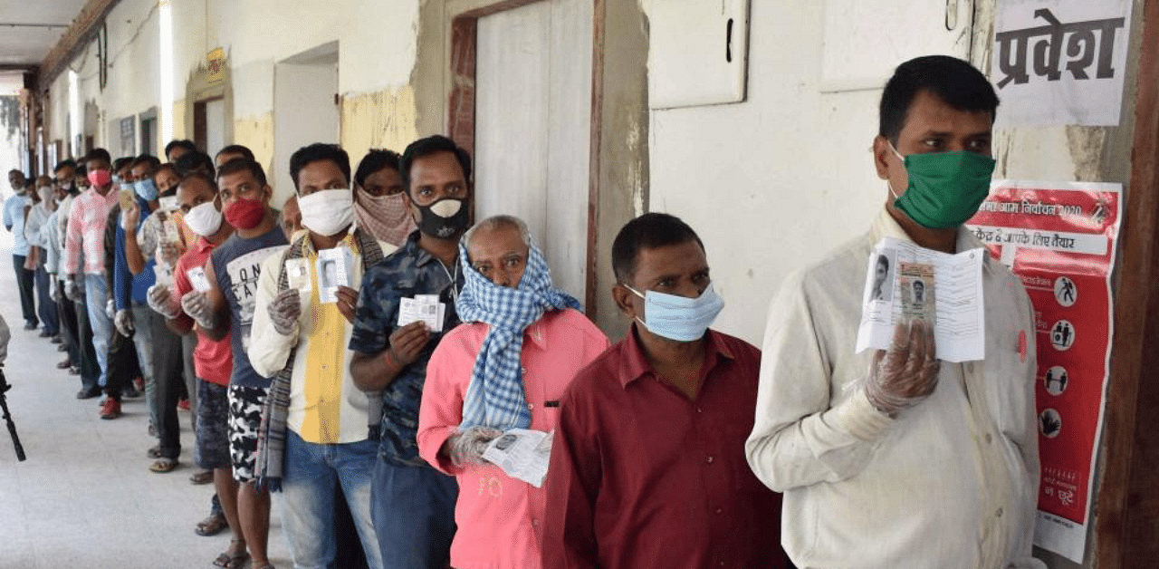  People stand in a queue to cast their votes during the first phase of Bihar assembly polls, amid the ongoing coronavirus pandemic, in Gaya, Wednesday, Oct. 28, 2020.  Credit: PTI Photo