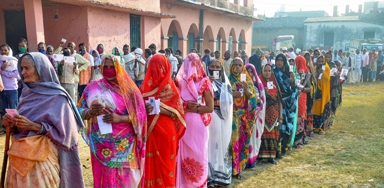 Voters stand in queues at a polling booth to cast their votes for the first phase of Bihar Assembly Election, amid the coronavirus pandemic, at Bhabhua police station in Kaimur district. Credit: PTI Photo