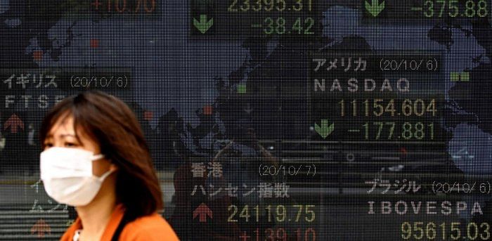 A pedestrian walks past an electronic quotation board displaying the Nikkei 225 index (C) with other stock market index of the Tokyo Stock Exchange in Tokyo. Credit: AFP Photo