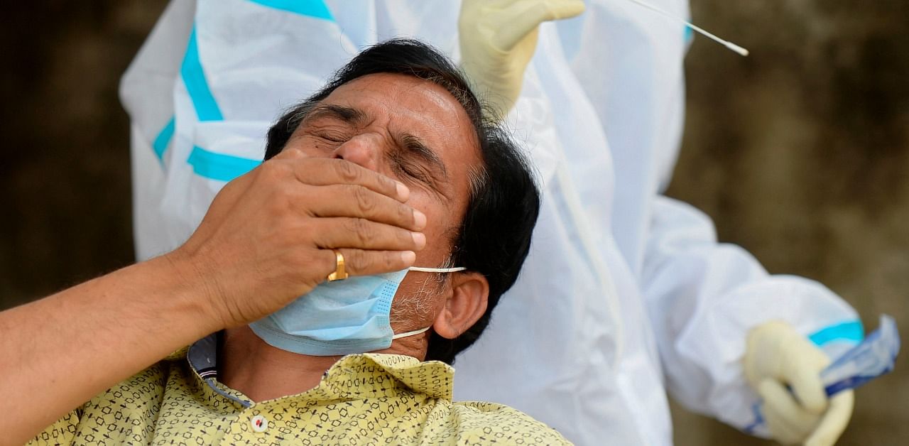A man reacts after a health worker took his swab sample to test for the Covid-19 at primary health centre. Credit: AFP Photo
