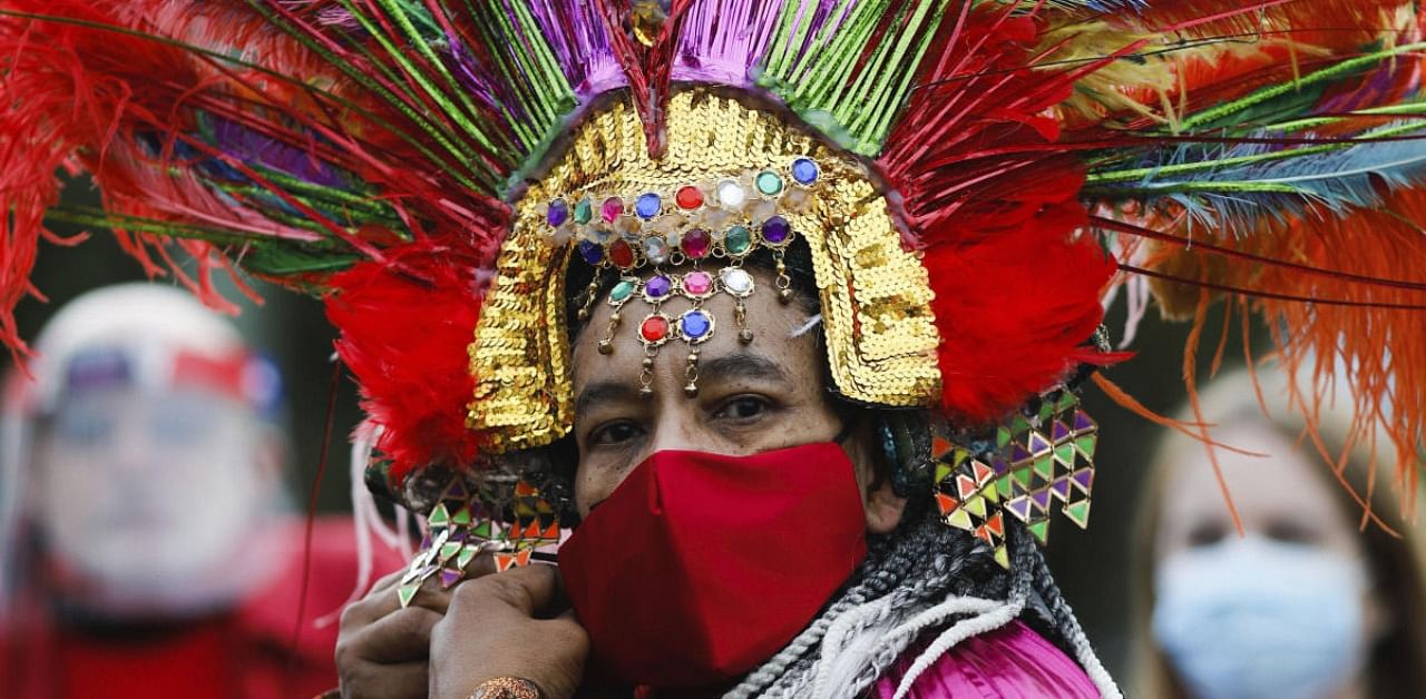 A man in a costume adjust his face mask as he attends a protest against the German government's economic policies to combat the spread of the coronavirus in Germany. Credit: AP/PTI Photo