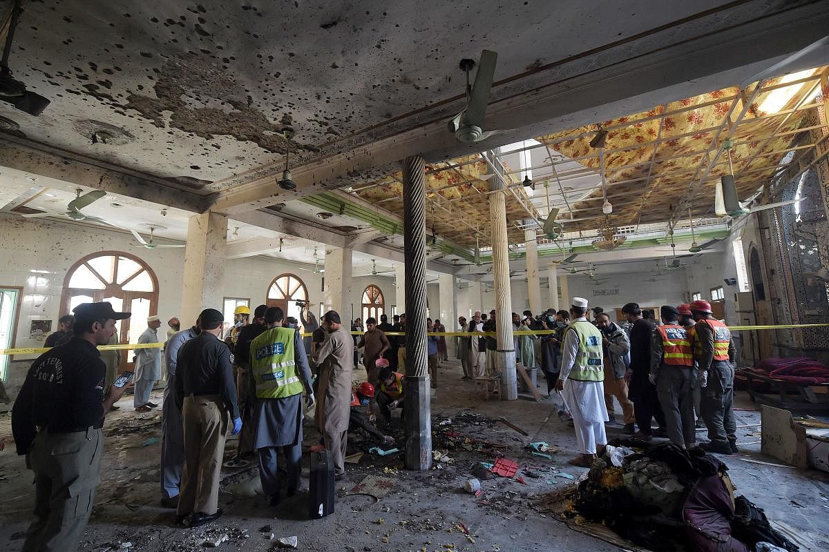 Security officials examine the site of a blast at a religious school in Peshawar. Credit: AFP
