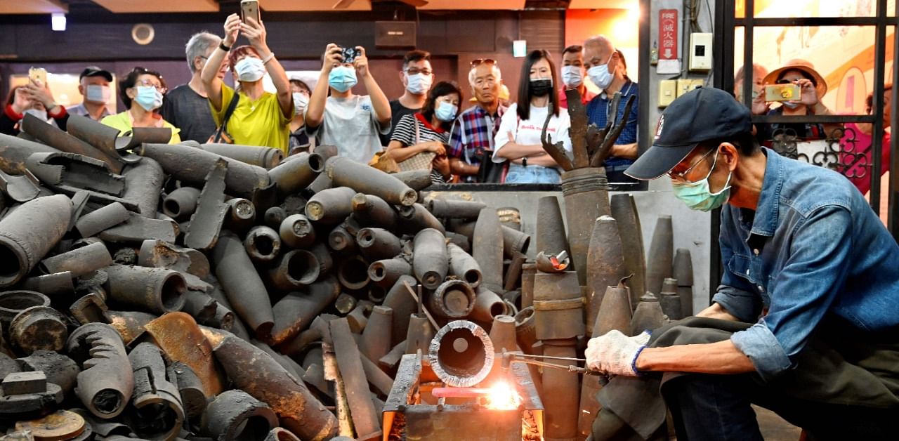 Taiwanese blacksmith Wu Tseng-dong (R), owner of a knife factory, giving a demonstration to tourists how to make a knife from cases of Chinese artillery shells which were fired decades ago from Xiamen on the mainland at Taiwan's Kinmen island - which lies off the coast of the Chinese mainland. Credit: AFP Photo