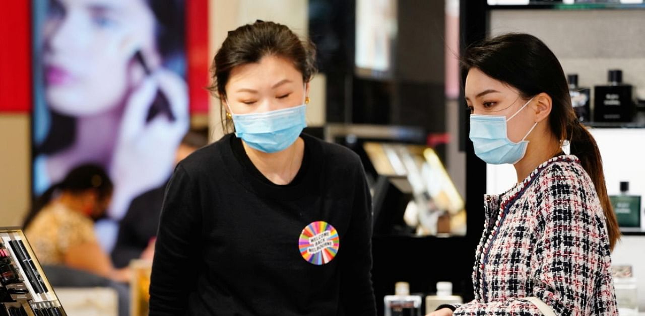 A shopper wearing a face mask is assisted in a retail store after coronavirus disease restrictions were eased in Melbourne. Credit: Reuters.