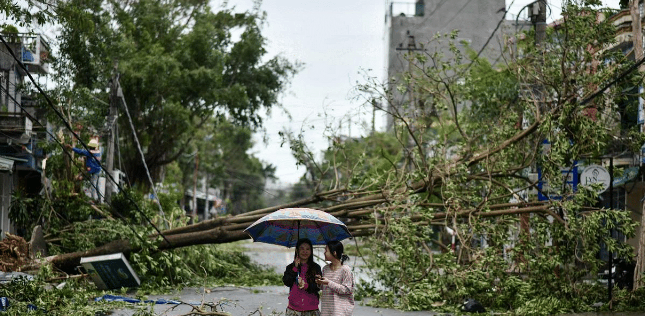 Women walk past uprooted trees in central Vietnam's Quang Ngai province in the aftermath of Typhoon Molave. Credit: AFP Photo