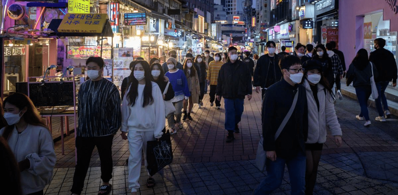 People wearing face masks walk on a street in the Hongdae district of Seoul amid coronavirus pandemic. Credit: AFP Photo