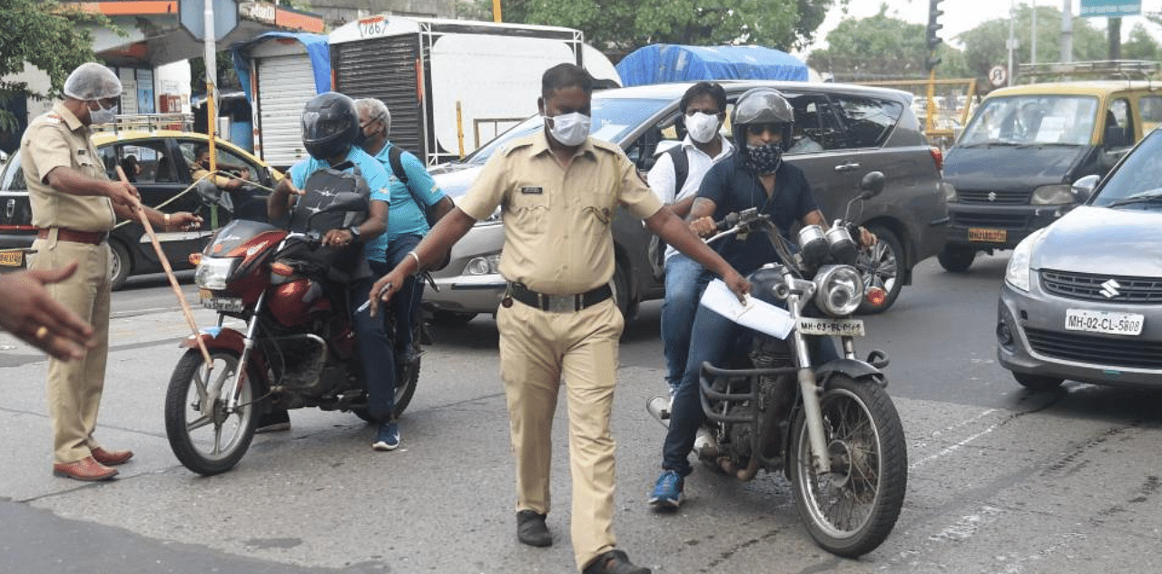  Police personnel stop motorists, who were violating lockdown norms by riding with a pillion, as coronavirus cases surge across the state during Unlock 2.0, in Mumbai, Monday, July 13, 2020. Credit: PTI Photo