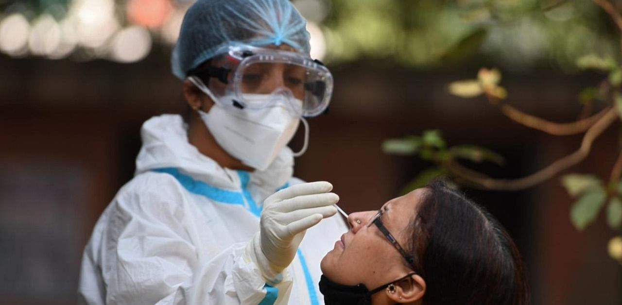A health worker collects a swab sample from a woman at a coronavirus screening site in New Delhi. Credit: AFP