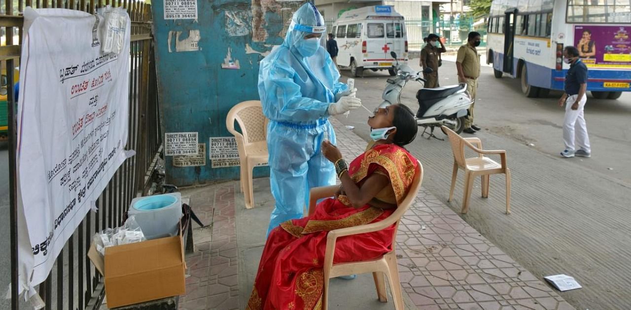 A health worker conducts swab test on a woman at a mobile coronavirus testing clinic at a bus stand in Bangalore. Credit: AFP