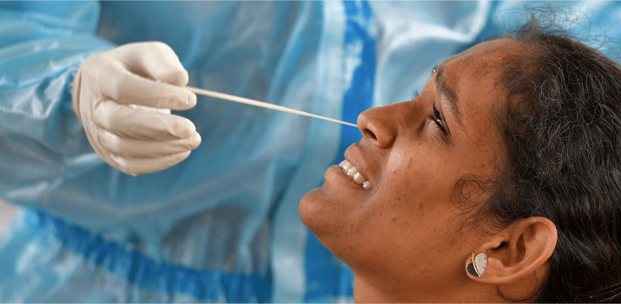 A health worker conducts swab test on a woman at a mobile Covid-19 coronavirus testing clinic at a bus stand in Bangalore. Credit: AFP