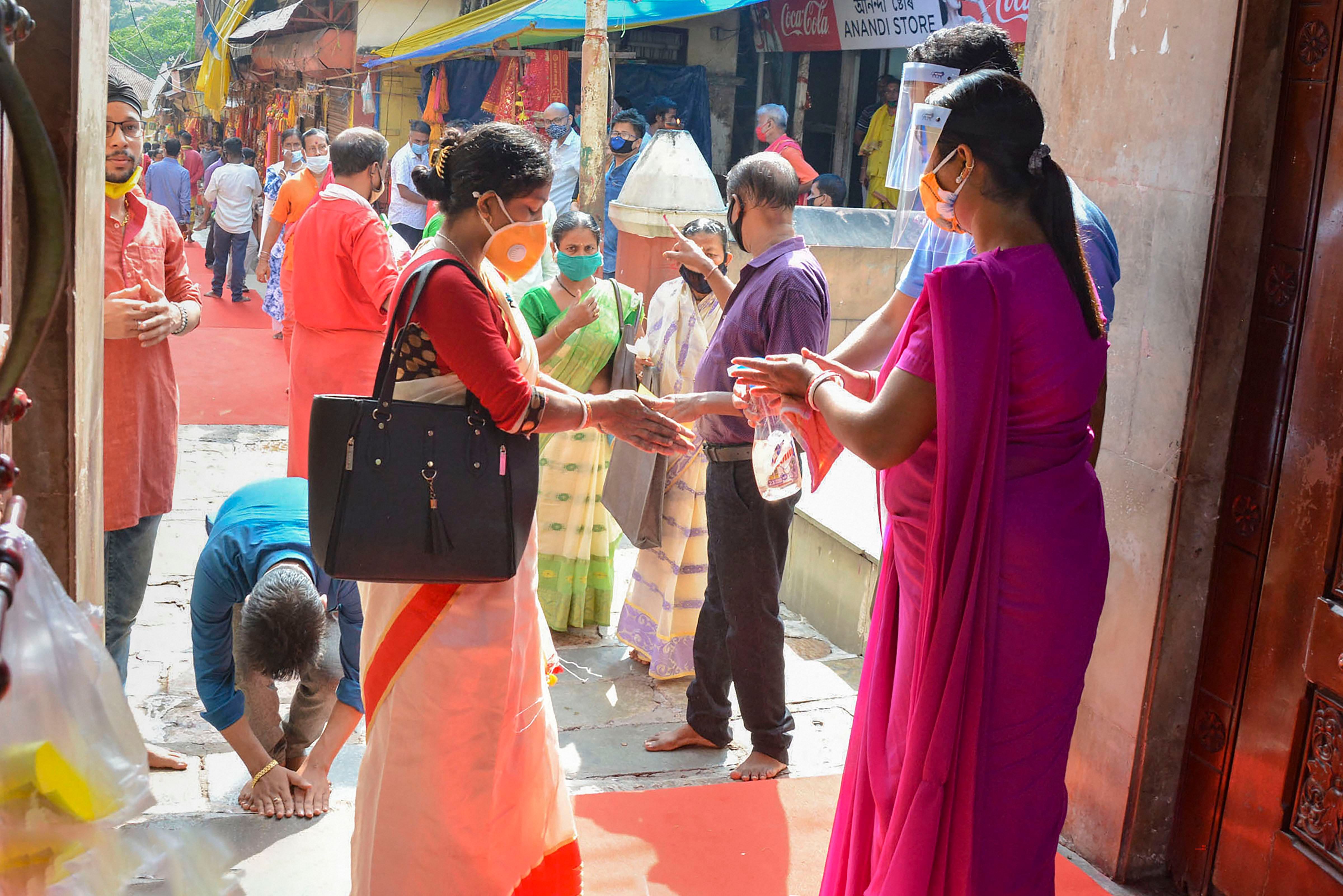 Devotees sanitise their hands inside the premises of Kamakhya Temple, as it re-opens for public after a gap of nearly six months due to coronavirus lockdown. Credits: PTI Photo