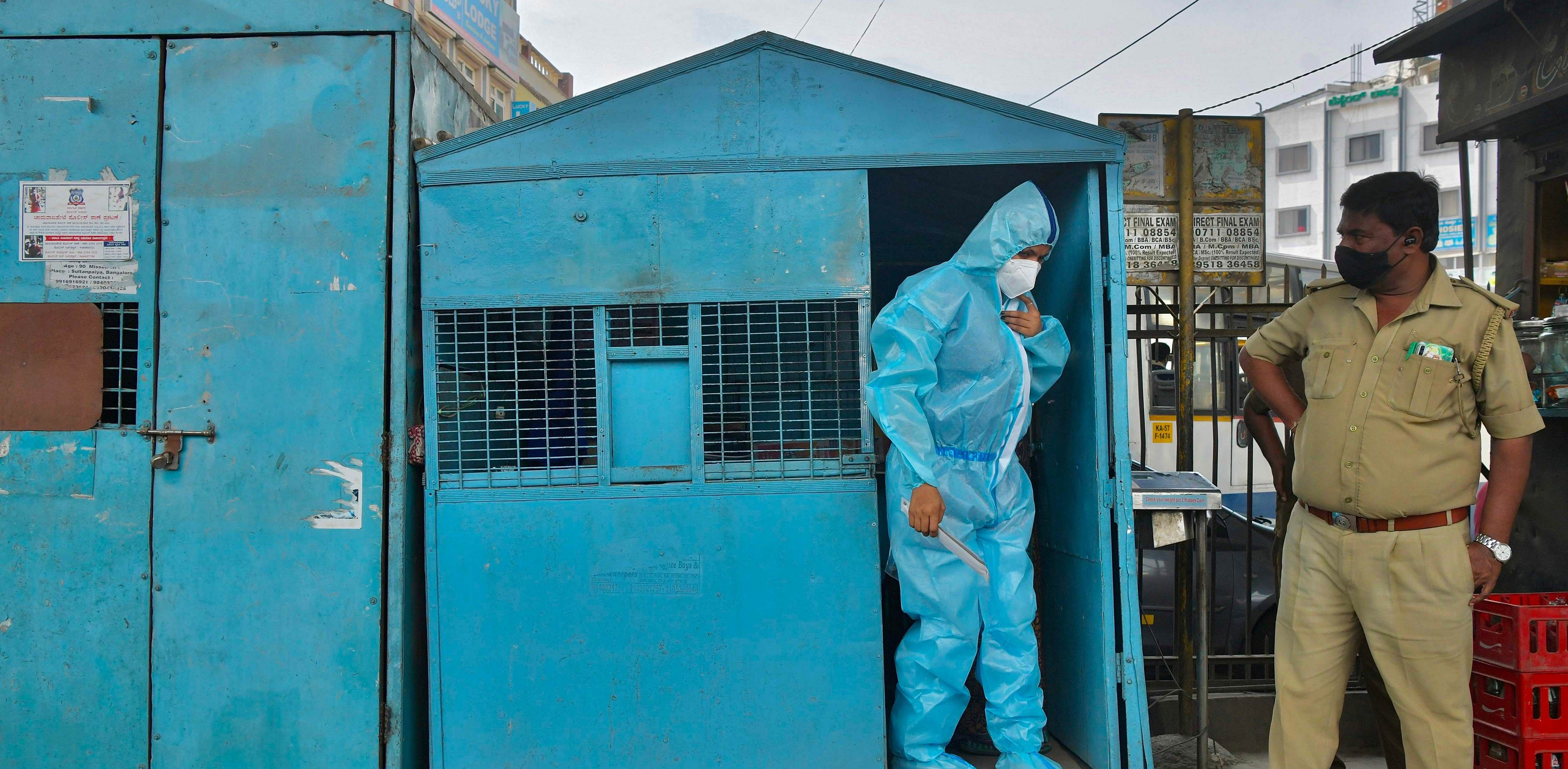 A health worker wearing protective gear prepares to conduct swab tests on people at a mobile Covid-19 coronavirus testing clinic at a bus stand in Bangalore. Credit: AFP