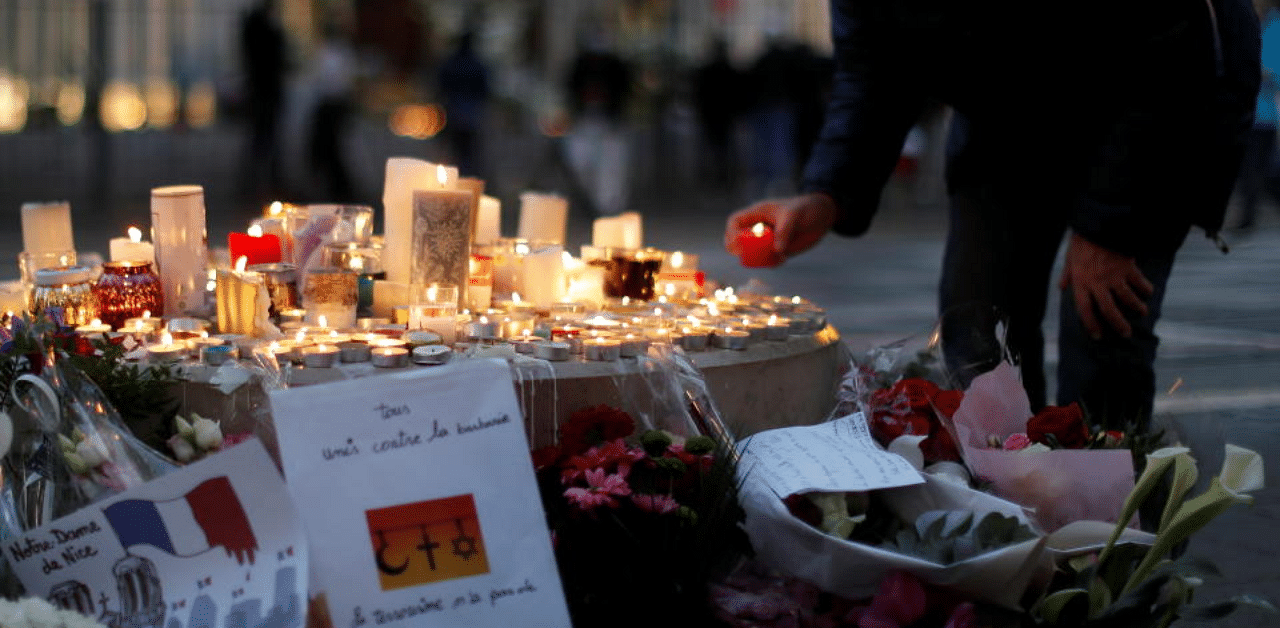 A man lights a candle near the Notre Dame church in tribute to the victims of a deadly knife attack in Nice, France, October 30, 2020. Credit: Reuters Photo
