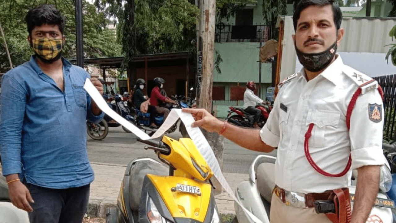 PSI Shivraj Kumar issues a fines receipt to rider Arun Kumar. Credit: DH.