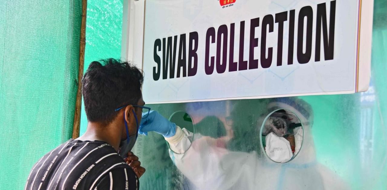 A health worker takes a swab sample from a man to test for coronavirus, as cases continue to spike, at a swab collection center in Guwahati. Credit: AFP