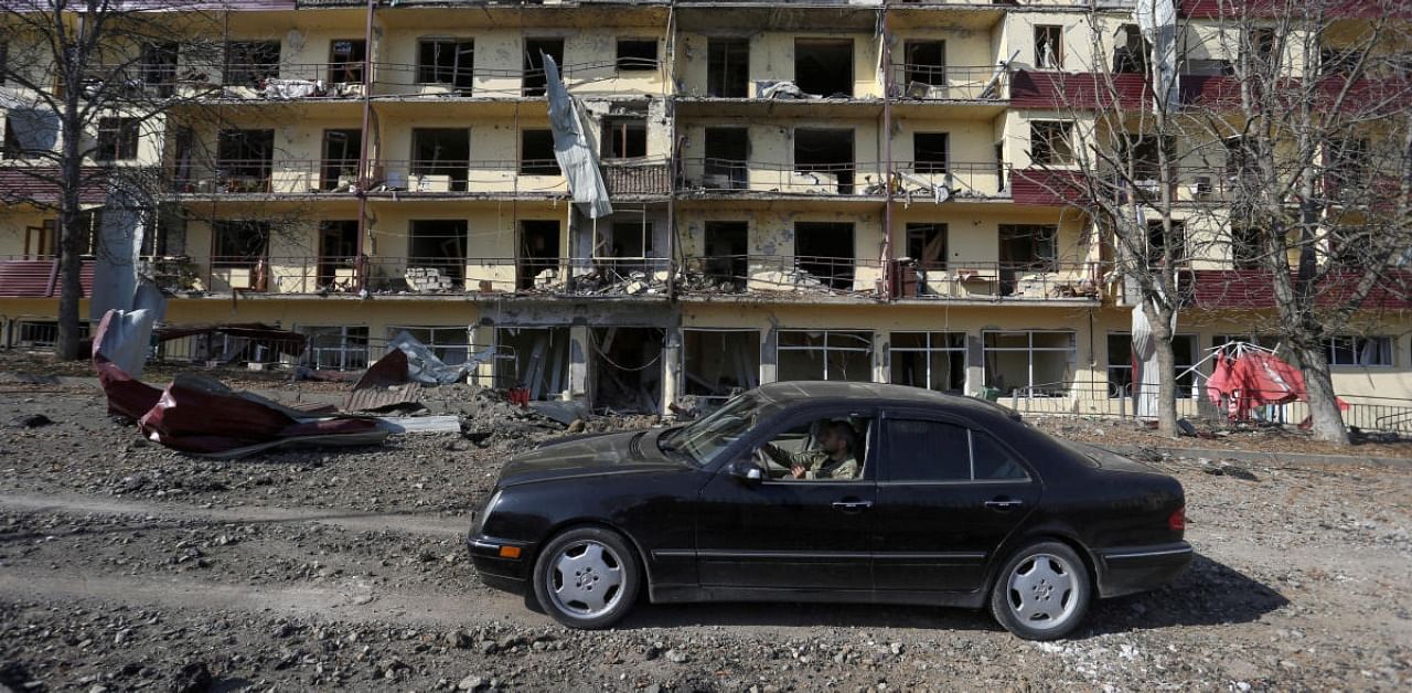 A man drives a car past a damaged building following recent shelling in the town of Shushi (Shusha), in the course of a military conflict over the breakaway region of Nagorno-Karabakh. Credit: Reuters Photo