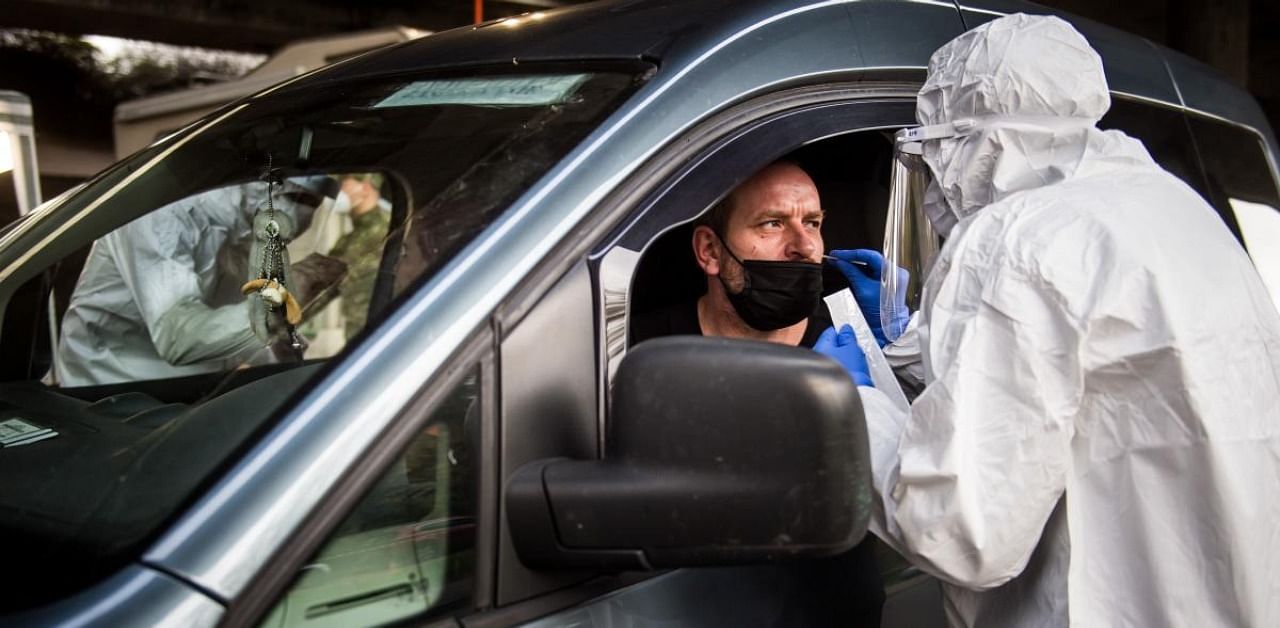Medic test a man in his car for the novel coronavirus during nationwide testing in an outdoor drive-through testing site in Bratislava, Slovakia. Credit: AFP