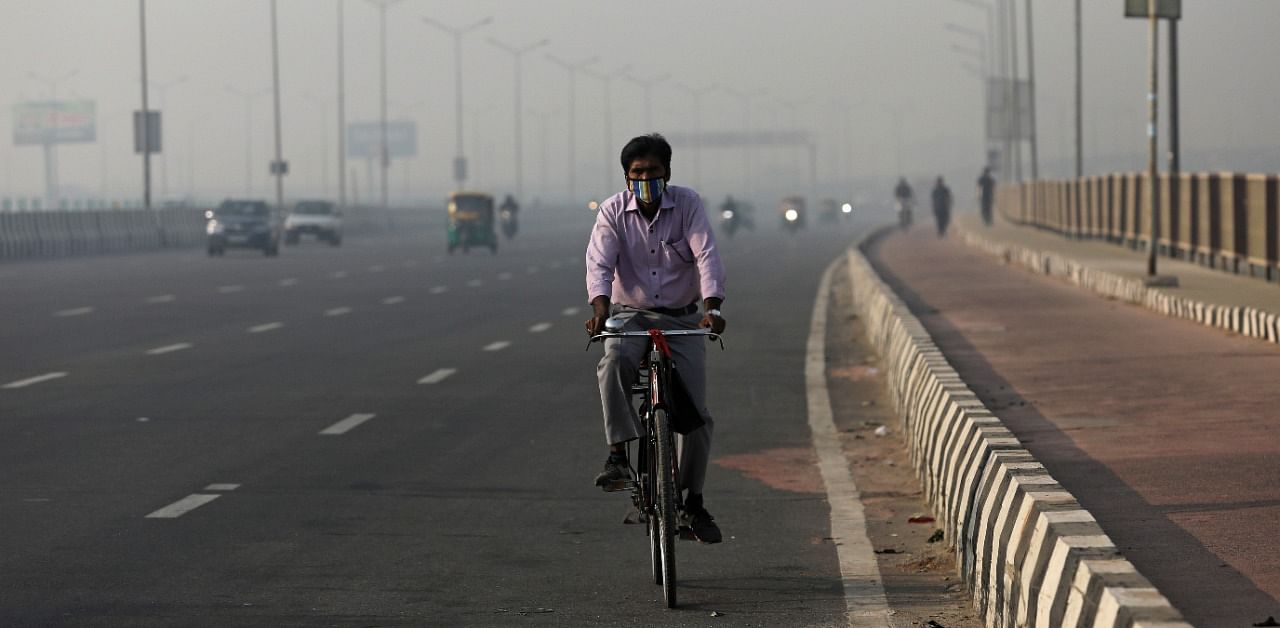 A man rides a bicycle along a highway on a smoggy morning in New Delhi, India. Credit: Reuters Photo