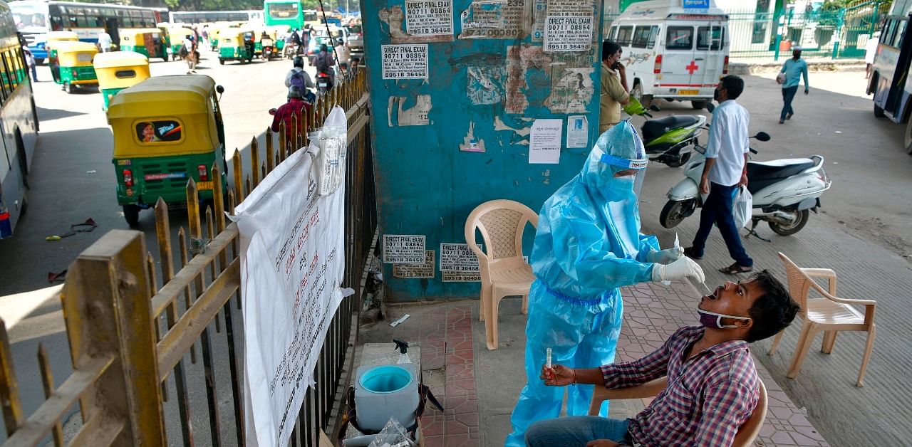 Health worker conducts swab test on a man at a mobile Covid-19 coronavirus testing clinic at a bus stand in Bangalore. Credit: AFP Photo