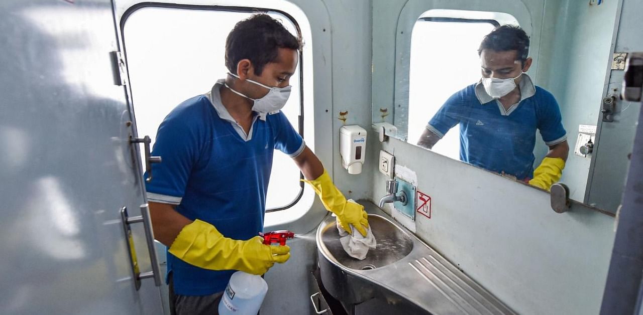 A railway worker disinfects a washroom of Howrah-New Delhi Rajdhani Express train in the wake of Coronavirus pandemic. Credit: PTI