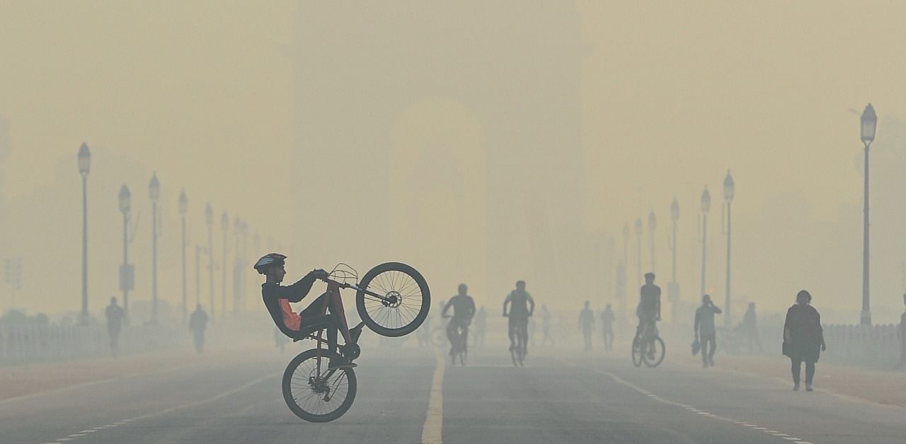 A cyclist performs stunts, during cold morning, amid hazy weather conditions, at Rajpath in New Delhi. Credit: PTI Photo