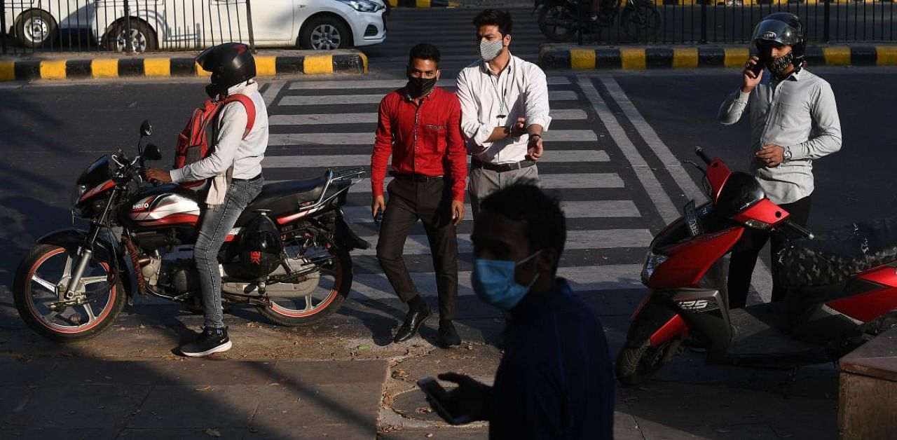 Pedestrians wearing facemasks as a preventive measure against Covid-19 walk on a road in New Delhi. Credit: AFP.