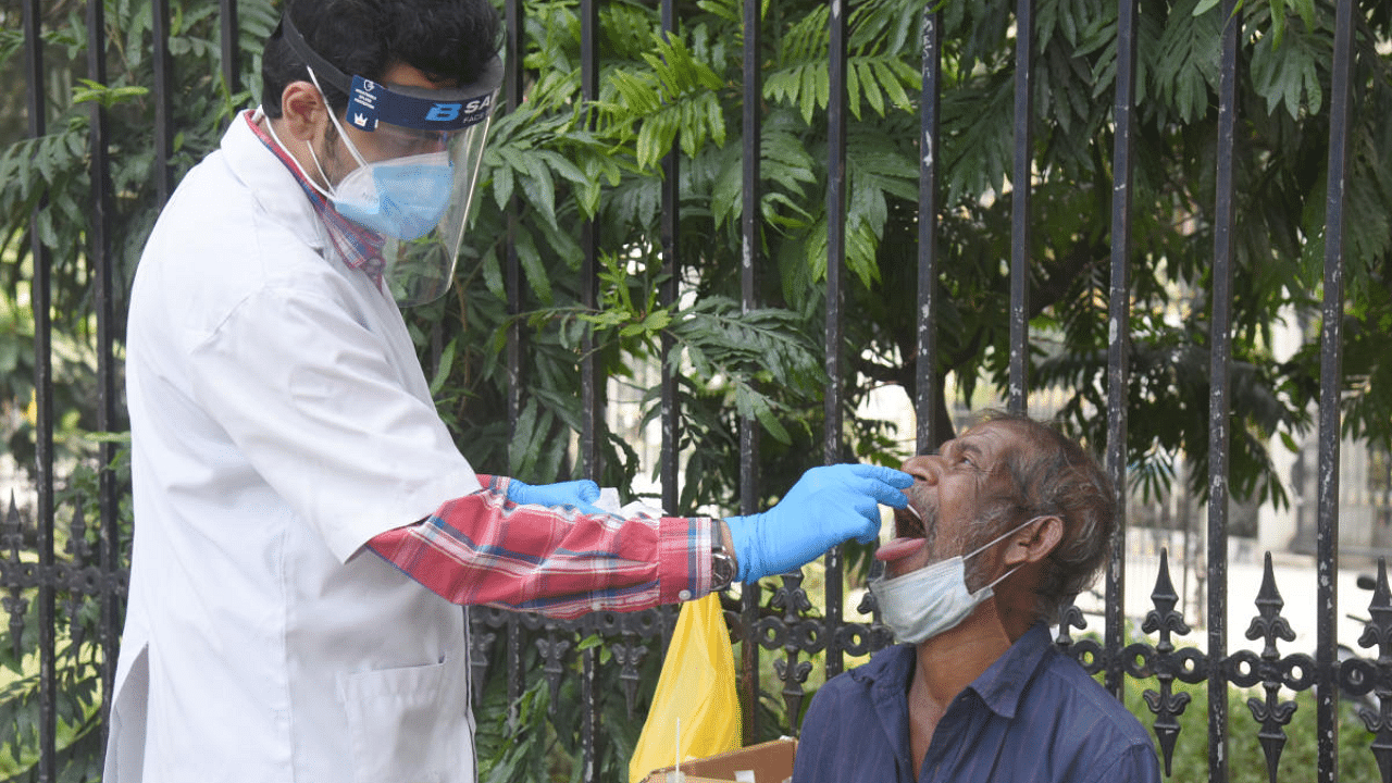 A healthcare worker takes the nasal swab of a man at a testing unit set up in front of the BBMP head office in Bengaluru on Sunday. Credits: DH Photo