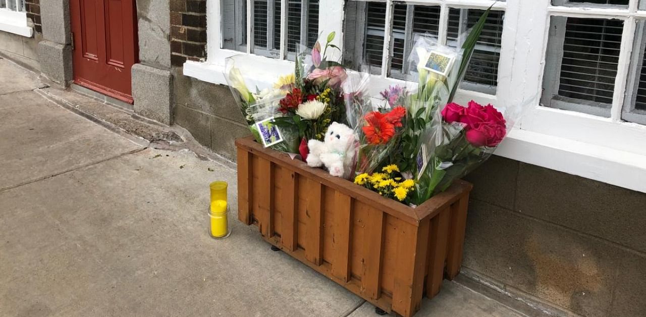 Flowers and a candle are placed in front of the house of a woman who died in Halloween attack in Quebec. Credit: AFP Photo