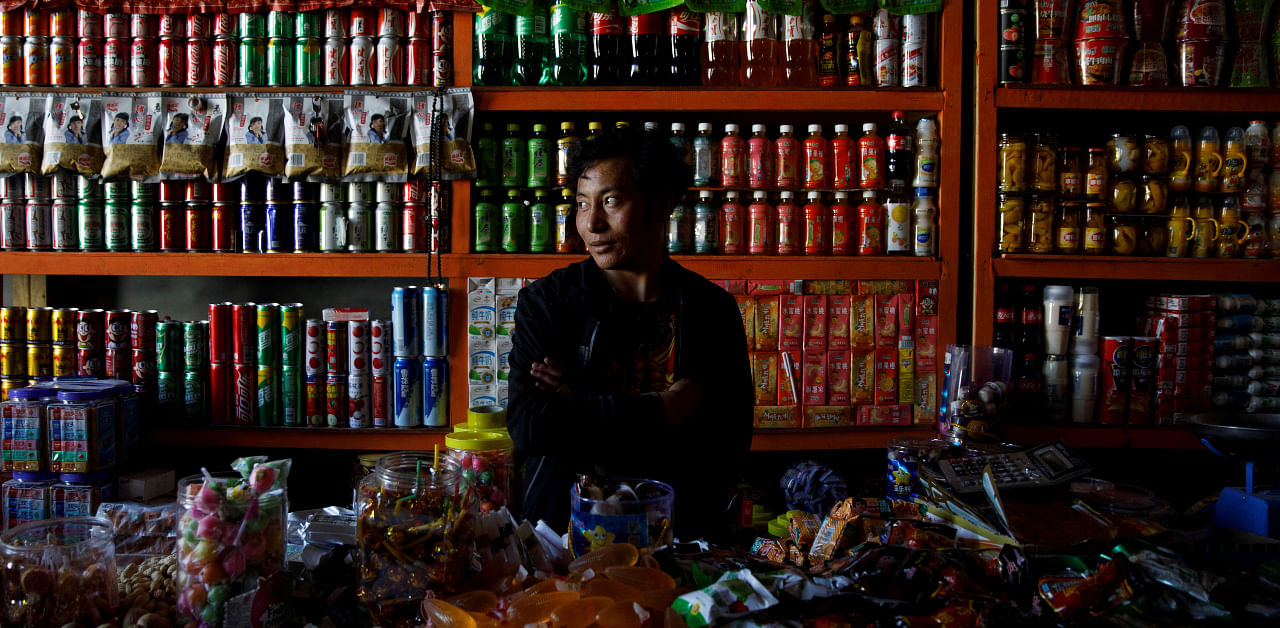 A man sells groceries in a shop in a village that the authorities built for Tibetans who have been relocated from high-altitude locations in what the authorities call poverty alleviation programs during a government organised tour in Gongga County, Lhoka City, near Lhasa, Tibet Autonomous Region, China. Credit: Reuters Photo