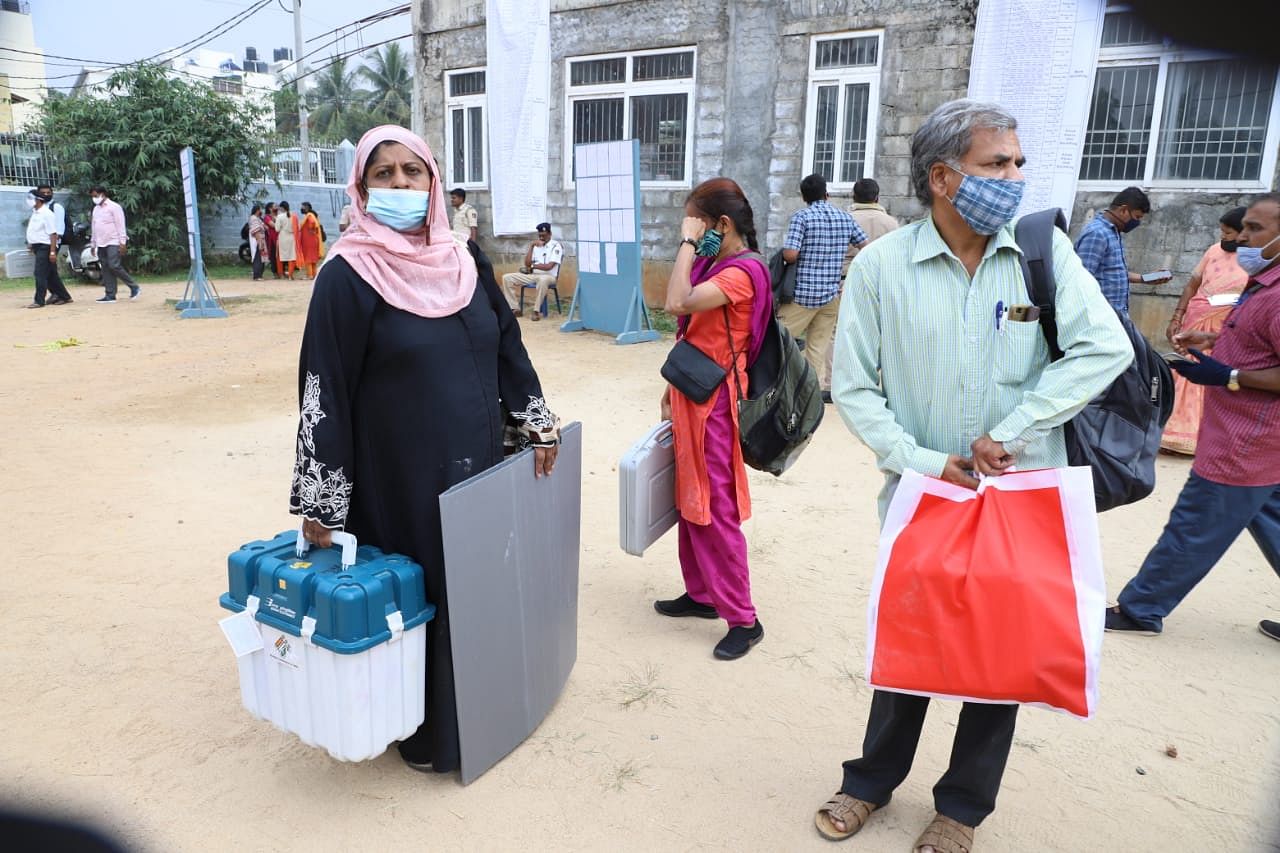 Poll officials on poll duty at 678 polling booths across RR Nagar were dispatched to their respective polling stations after collecting EVMs and VVPAT machines from the mustering centres. Credit: DH Photo