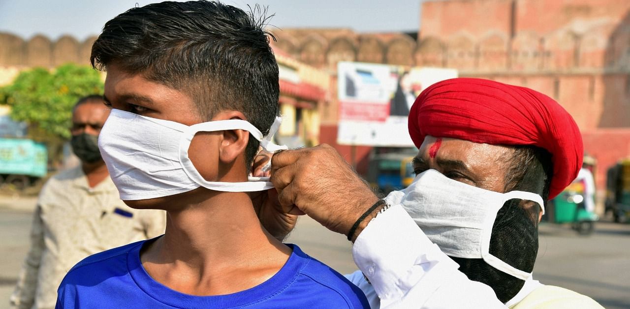 A social worker puts a face mask on a boy in the wake of coronavirus pandemic during an awareness drive, in Bikaner. Credit: PTI Photo