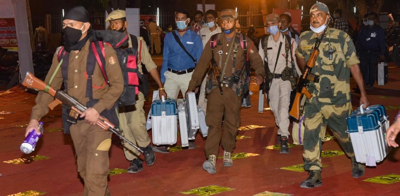 Security personnel and polling officers carry Electronic Voting Machines (EVMs) to deposit at a strong room after the second phase of Bihar Assembly polls. Credit: PTI.