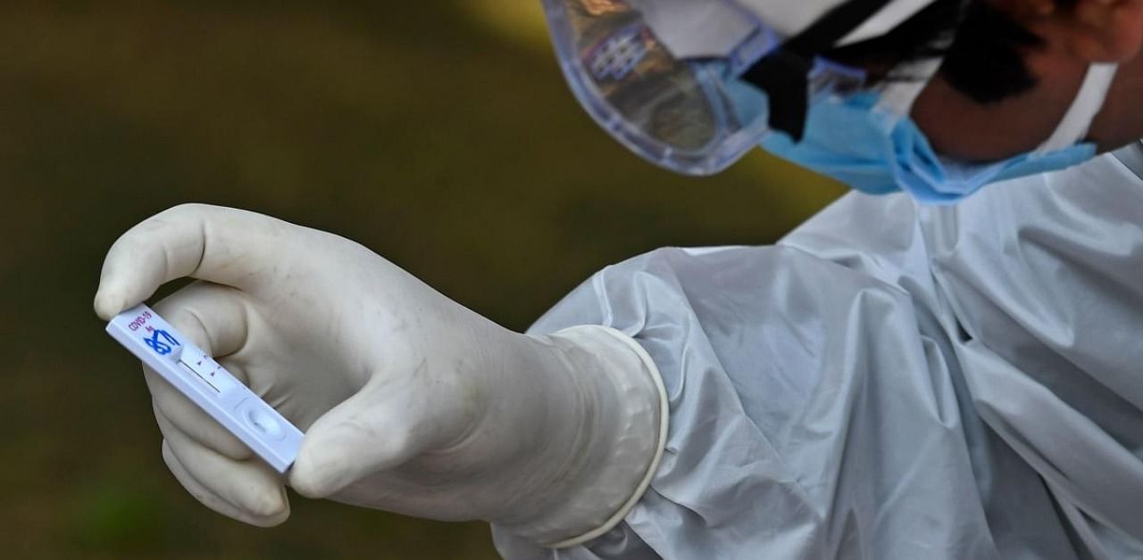 A health worker checks a nasal swab sample collected from a resident during a Rapid Antigen Test (RAT) for the Covid-19. Credit: AFP