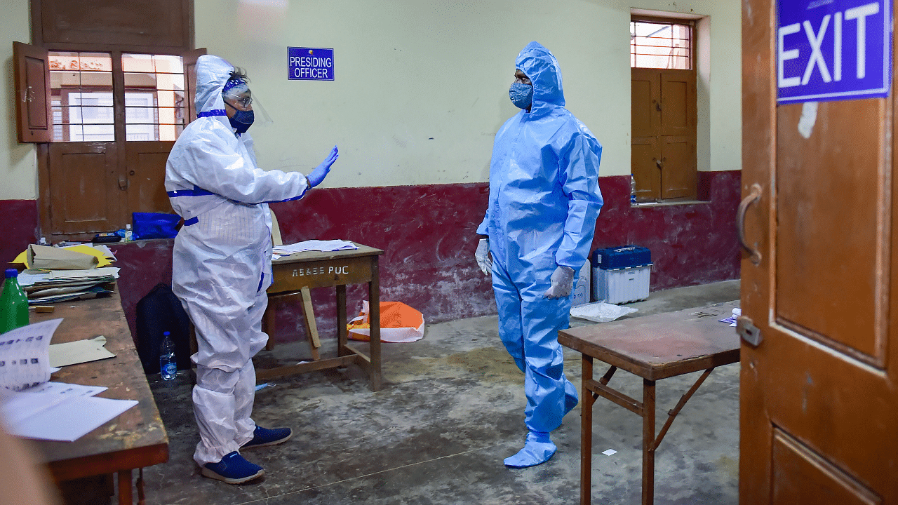 A Covid-19 patient arrives to cast his vote for the state by-polls, at Rajarajeshwari Nagar in Bengaluru. Credits: PTI Photo