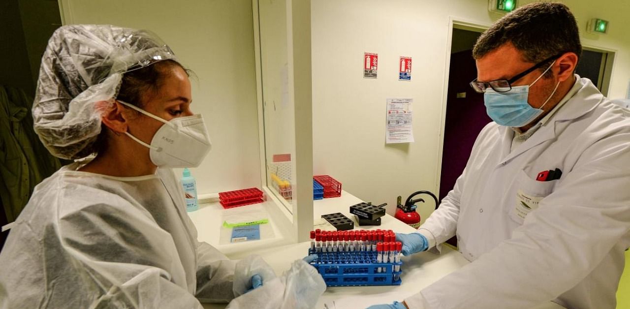 A health worker (L) presents swab samples for a coronavirus. Credit: AFP