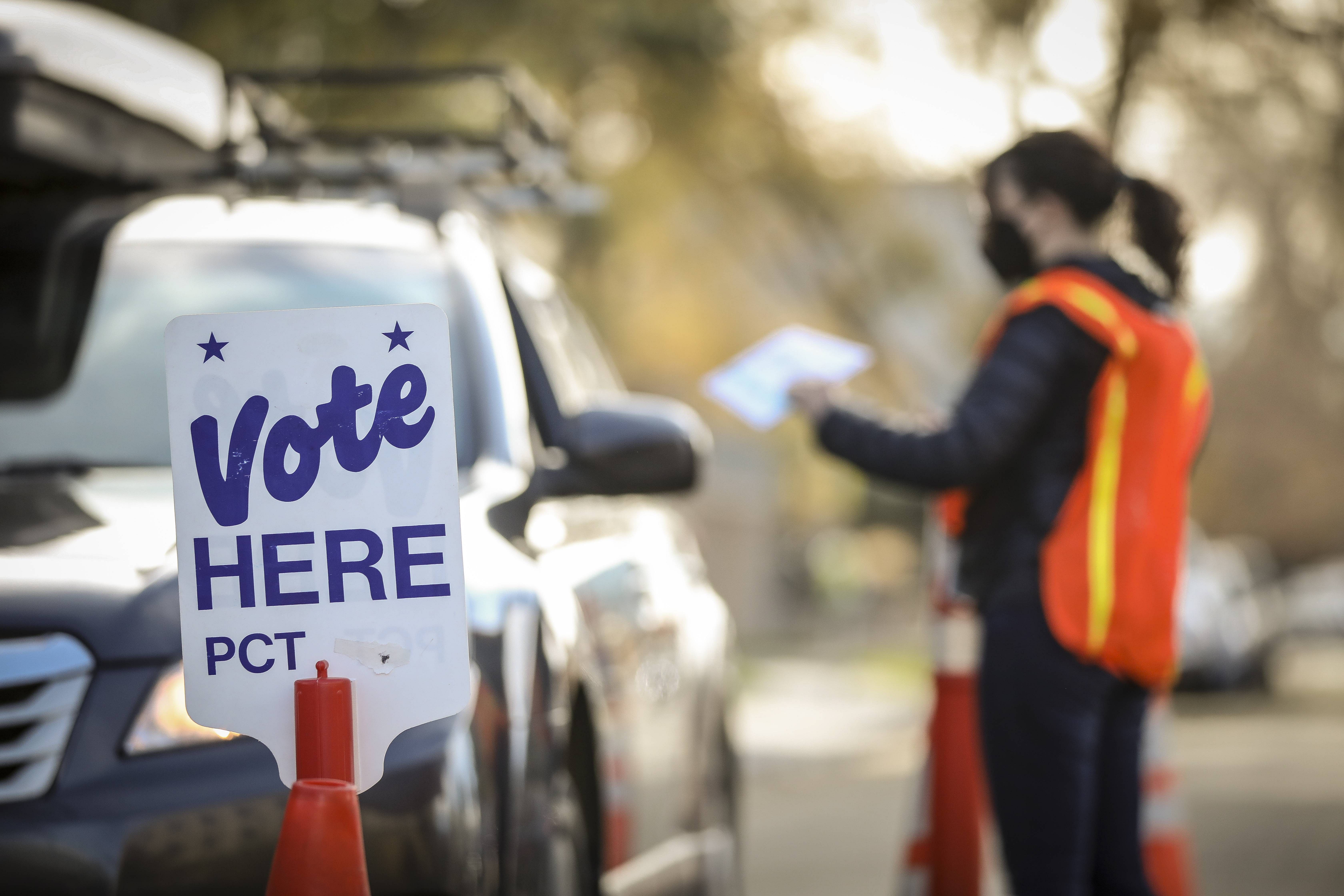 An election judge accepts a ballot at a drive-thru ballot drop location outside the Denver Elections Division Building. Credits: AFP Photo