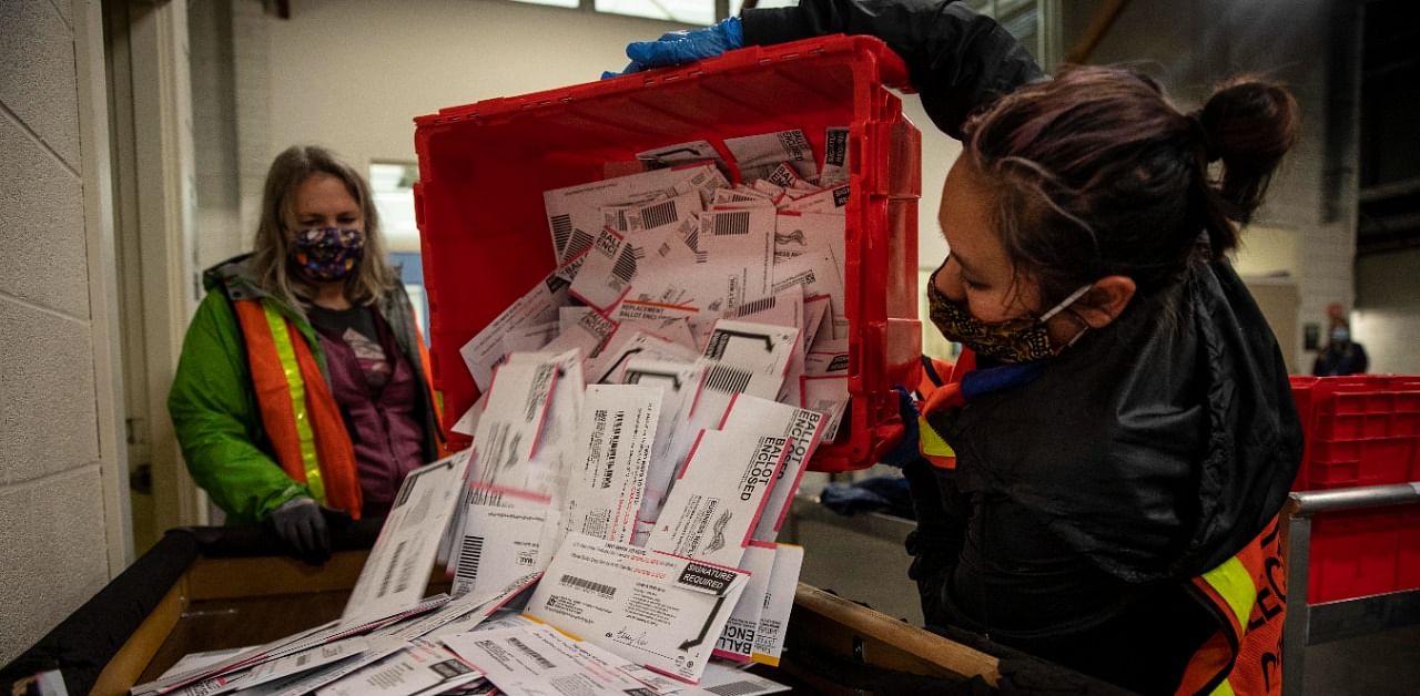 Election worker Kristen Mun from Portland empties ballots from a ballot box at the Multnomah County Elections Division. Credit: AP/PTI