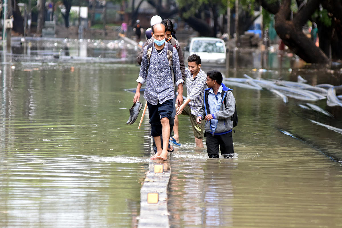 People struggle to cross inundated 80 Ft Road in Koramangala in April. Every year, several parts of Koramangala are waterlogged. DH Photo S K Dinesh