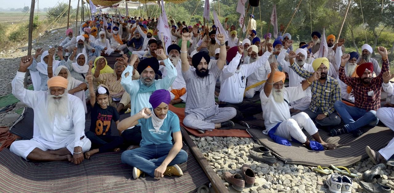  Farmers shout slogans during their ongoing 'Rail Roko' protest over new farm laws, at Devi Dass Pura village in Amritsar. Credit: PTI Photo