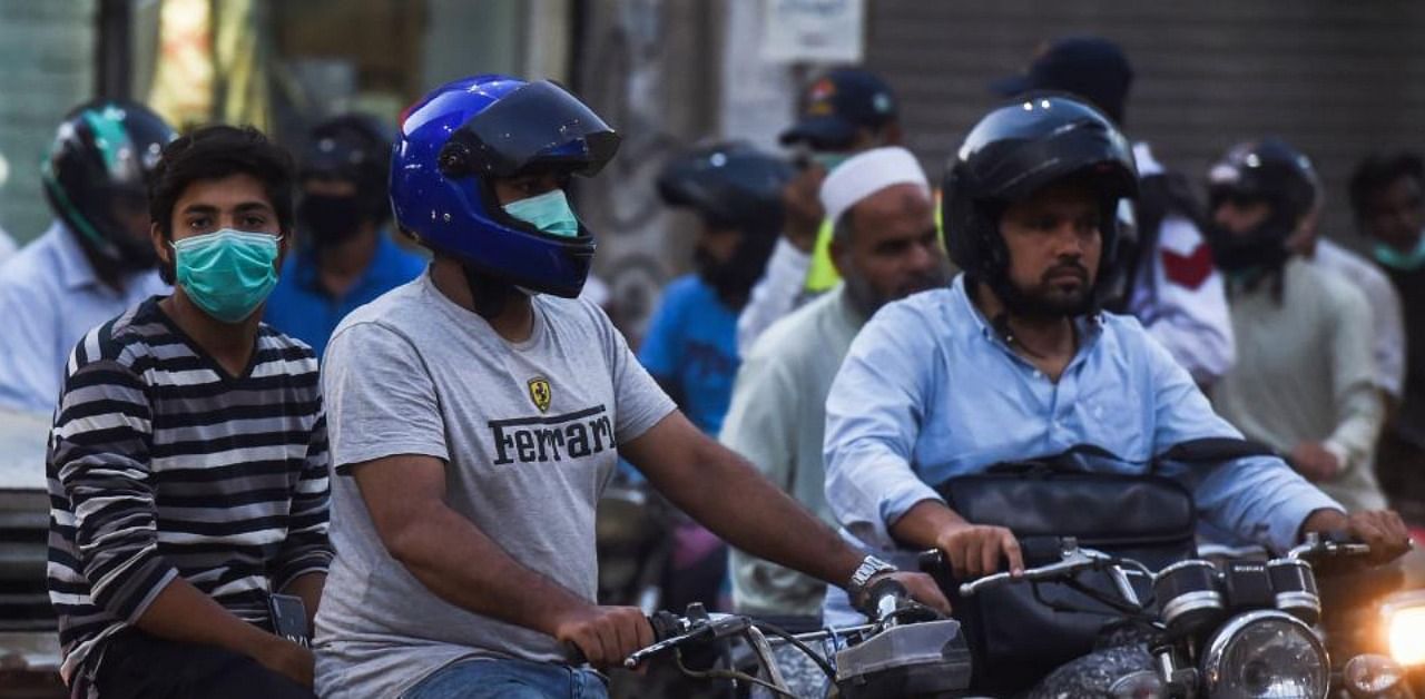 Motorists riding motorbikes along a street wear facemasks as a preventive measure against the Covid-19 coronavirus, in Karachi. Credit: AFP.