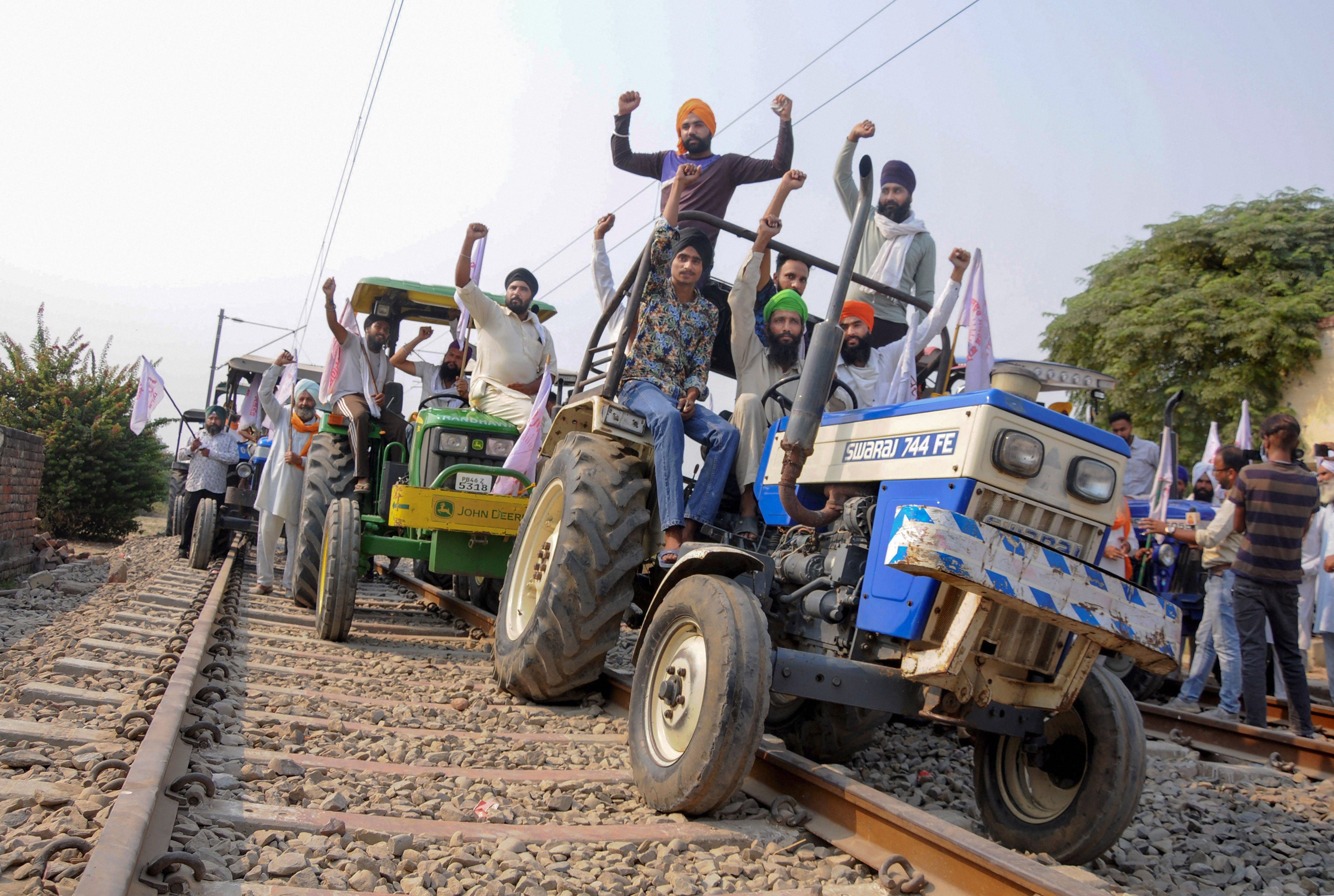 Farmers raise slogans as they block train tracks with tractors on the twentieth day of their ongoing 'Rail Roko' protest over recent farm reform bills, at Devi Dass Pura village in Amritsar, Tuesday, Oct. 13, 2020. Credit: PTI Photo