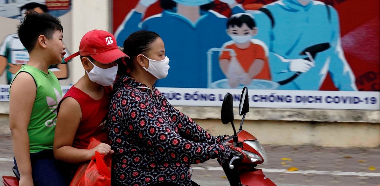 A woman wears a protective mask as she drives past a banner promoting prevention against the coronavirus disease in Hanoi, Vietnam. Credit: Reuters Photo
