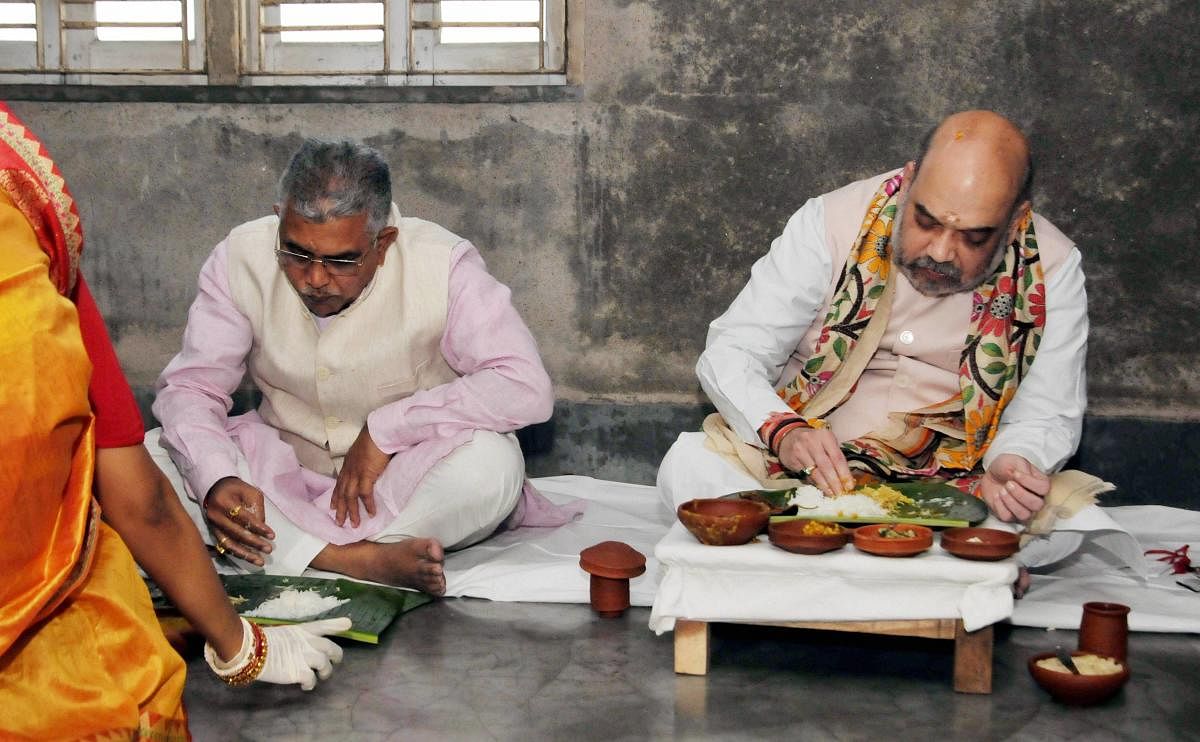 Union Home Minister Amit Shah and BJP State President Dilip Ghosh (L) eat lunch with a Matua family at their residence at Gouanganagar in Kolkata. Credit: PTI