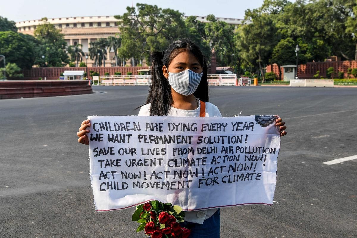 Child environmental activist Licypriya Kangujam, 9, holds a banner during a solo demonstration in front of the Parliament to protest against the inaction of the government to fight the capital's air pollution in New Delhi. Credits: AFP File Photo