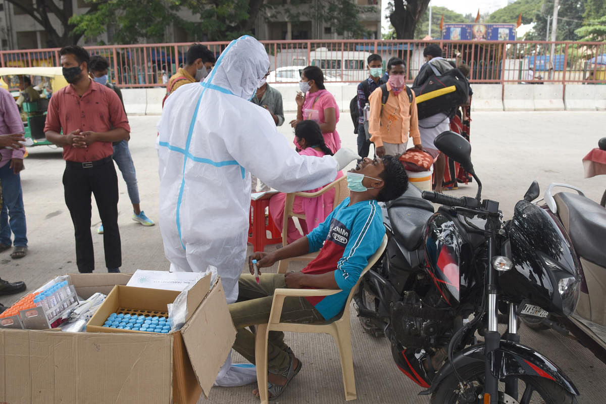 Health workers collect nasal swabs from the public at a roadside check-up camp organised by the BBMP in Majestic, Bengaluru, on Thursday. DH Photo/S K Dinesh