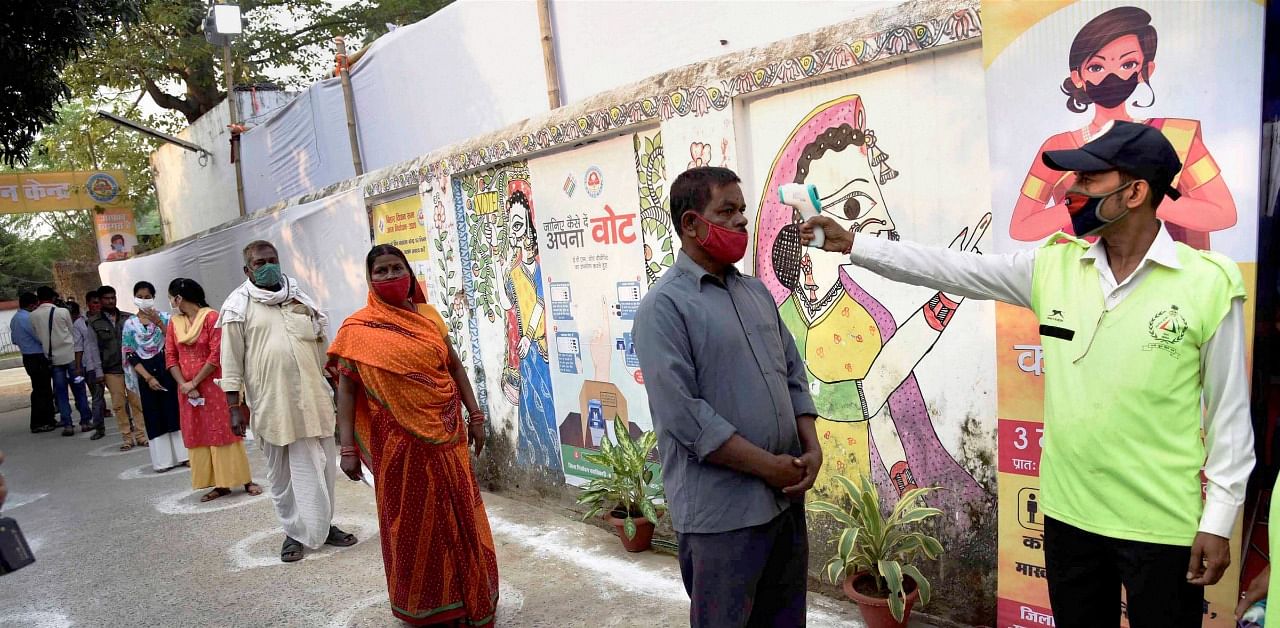 Voters undergo thermal screening at a polling station before casting his vote during the second phase of Bihar assembly elections, amid the ongoing coronavirus pandemic. Credit: PTI Photo